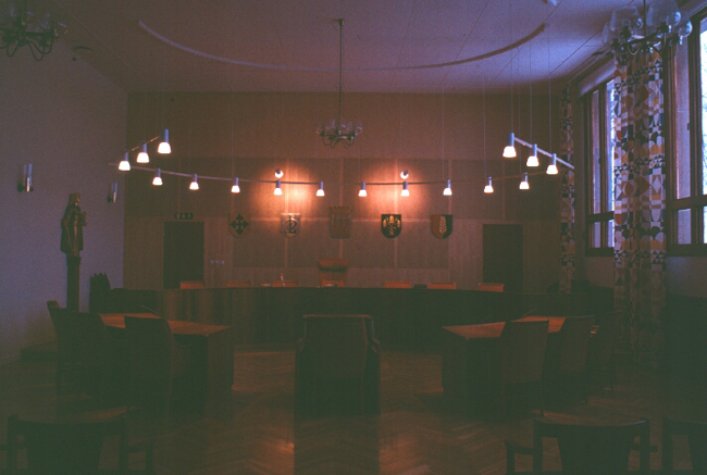 Tingssalen, vanligtvis väldigt ljus, med sina teakfönster, Joseph Frank-textilier och Justitiastaty till vänster i bild. Vy mot podiet.