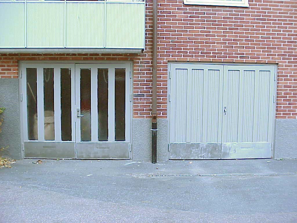 Garageport och källarentré samt balkongfront åt södra gården. Notera dörrarnas likhet, där panelfyllningarna bytts mot glas.