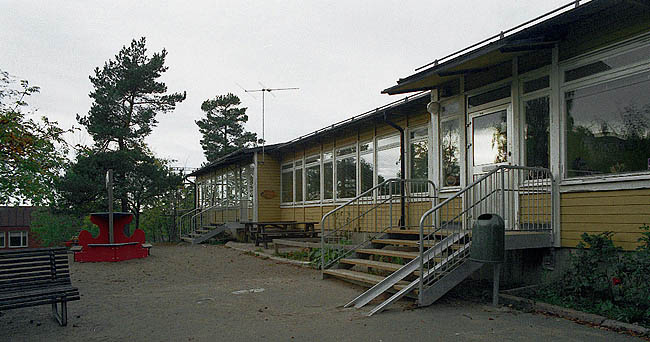 *SAK00057_ Stockholm, Bredäng, Concordia 3, del av, Concordiavägen 27,29_ Daghemmets fasad mot gården, med lekplatser. Fotografiet taget från sydost.

