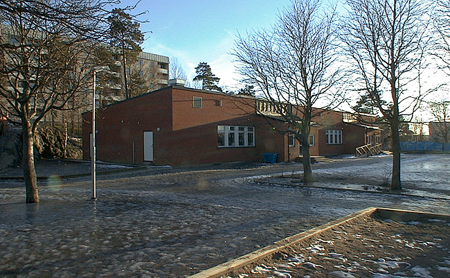 Den nya klassrumsbyggnaden med fasader i tegel. 

SAK02027 Stockholm, Skärholmen, Falkholmen 3, Stångholmsbacken 91-95, från nordväst (hus 7)