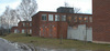SAK02117 Stockholm, Skärholmen, Österholmen 1, Ekholmsvägen 41-43, från nordväst. 

Huvudbyggnadens fyra flyglar. Det närmsta gårdsrummet slutes av ett gråmålat plank samt ett växthus i tegel.