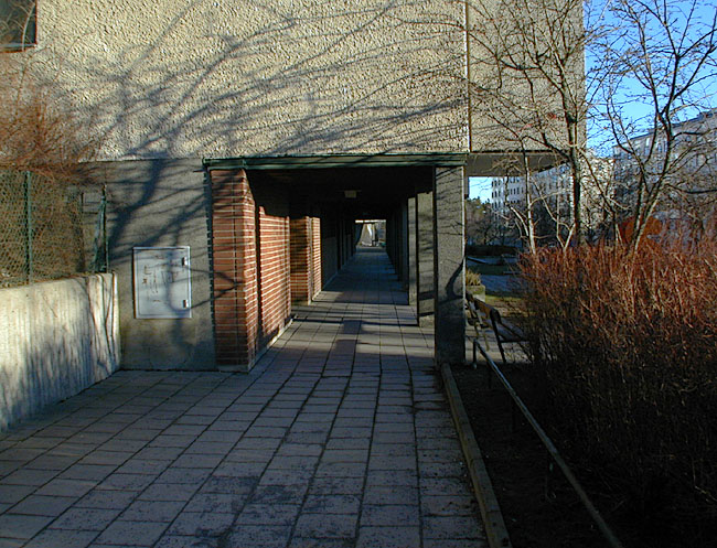 Skärholmen, Harholmen 3 , Äspholmsvägen 3-49.

Många av skivhusen har en arkad med betongpelare på entrésidans botten- eller suterrängvåning, med fasad i rött tegel. Bild från väster på en av byggnaderna norr om Äspholmsvägen.