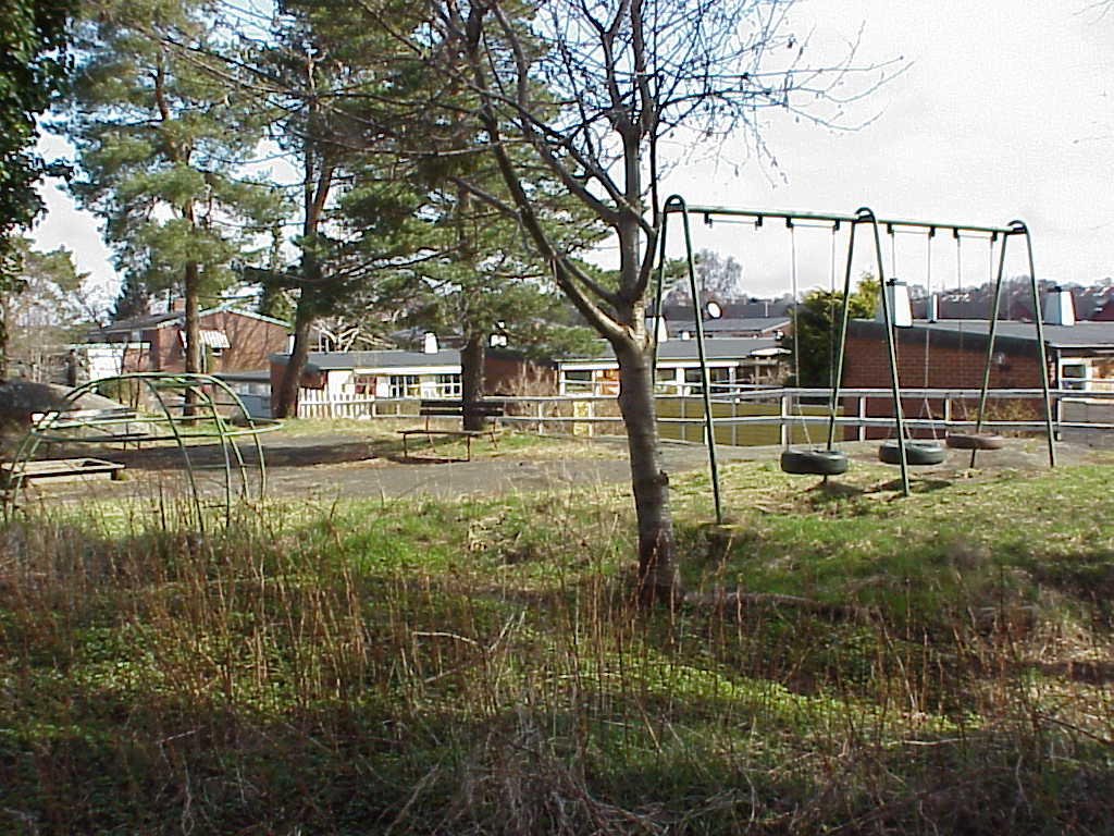 På en kulle i väst finns en samtida lekplats, gränsande till äldre villatomter.