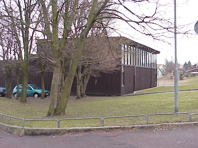 Gymnastikbyggnadens västfasad. Initll byggnadens högra sida kan det näraliggande daghemmet anas i bakgrunden.