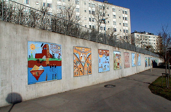 Tensta, Islinge 2, Mellingebacken 22.

Mot det högre marken utanför området i väster finns en hög betongmur, dekorerad av färgglada målningar.
 