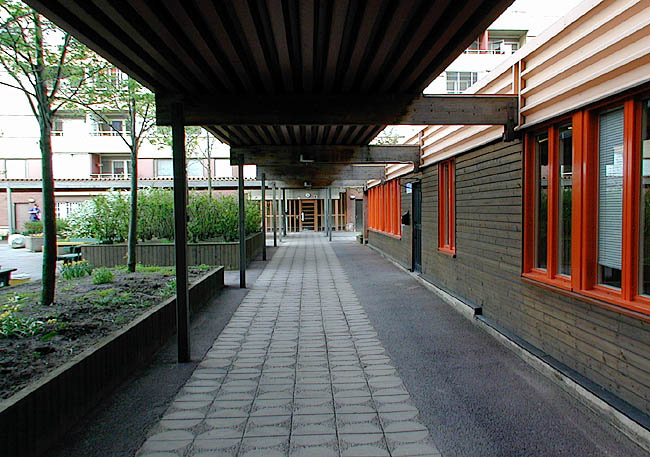 Akalla, Nystad 1 samt 7-11, Sibeliusgången.

Regnskyddat gångstråk mellan husens entréer. Till höger tvättstugan, vars färgsättning harmonierar med gårdens övriga byggnader.