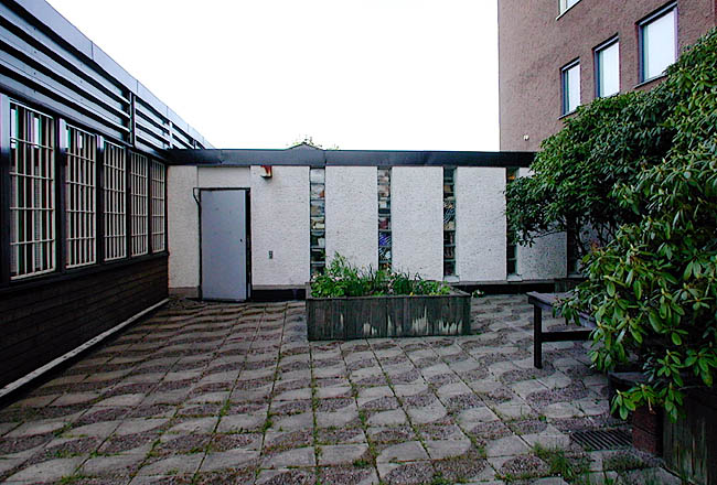 Akalla, Nystad 1 samt 7-11, Sibeliusgången 14.

Parti som binder samman Frälsningsarméns lokal och skivhuset. I de smala muröppningarna sitter betongglas.