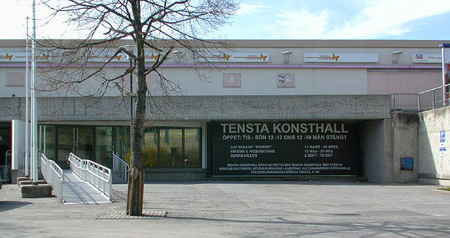 Tensta konsthall ligger sedan 1998 i centrumhusets suterrängvåning 
med entré mot parkeringsplatsen vid Taxingegränd. Lokalerna innehöll ursprungligen lager. 

SAK07375 Sthlm, Tensta, Bränninge 2,3,4, Tenstagången 8-49, från sydost


















