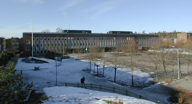 Klassrumsbyggnaden och den trädomgärdade skolgården. 
SAK03912 Sthlm, Vårberg, Byholmen 1, Vårholmsbackarna 100, från sydost









