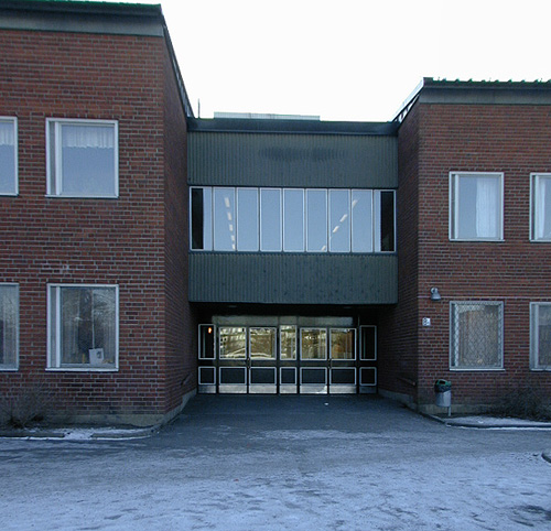 Entré slöjd- och matsalsbyggnaden. 
SAK03910 Sthlm, Vårberg, Byholmen 1, Vårholmsbackarna 100, från norr










