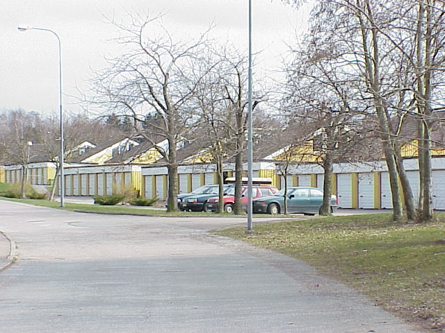 Vy mot parkeringsplatser och garage som ligger längs Hallstensvägen på områdets norra sida.