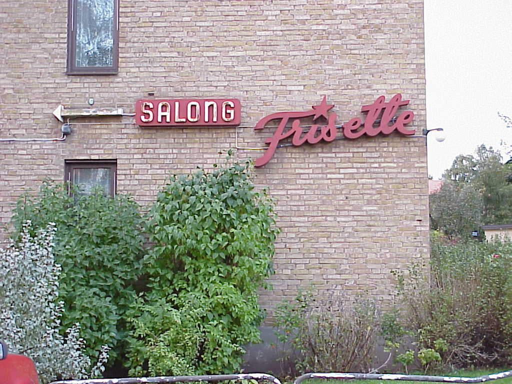 Områdets enda lokal - "Salong Frisette" - annonseras med neonljus på fasaden mot områdets entré från Blåsvädersgatan i norr.