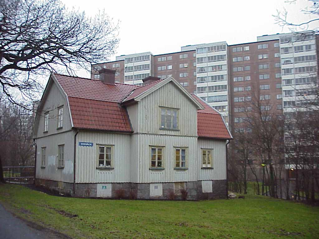 Huvudbyggnaden av f.d. gården Ekebäcken på sin ursprungliga plats, mellan höghus i öst, Frölunda kulturhus i väst och Frölunda torg i syd.