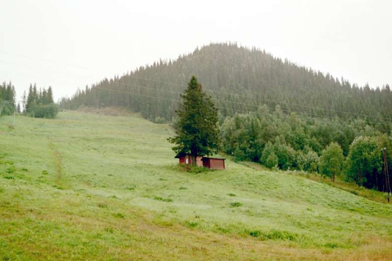 Värmestuga och förråd med Totthummeln i fonden. Foto från väster.