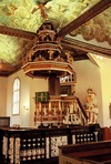 Predikstolen med sitt imponerande ljudtak. Tillverkad för Göteborgs domkyrka på 1630-talet, uppsatt i Kungälvs kyrka av Nils Persson. Skranket nedanför predikstolen inramar dopplatsen. 