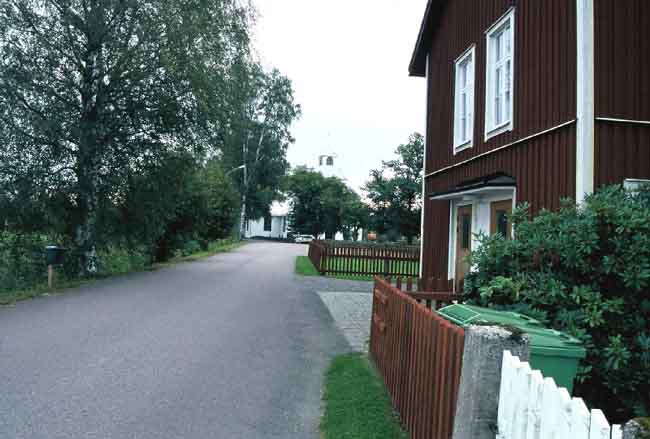 Övre Ulleruds kyrka från väster. Vägen fram till kyrkan passerar sockenstugan.