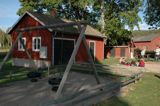 Edsleskogs prästgård, vy från sydväst,  lekplats för daghem/förskola, i förgrunden garage och i bakgrunden en f.d. vedbod.