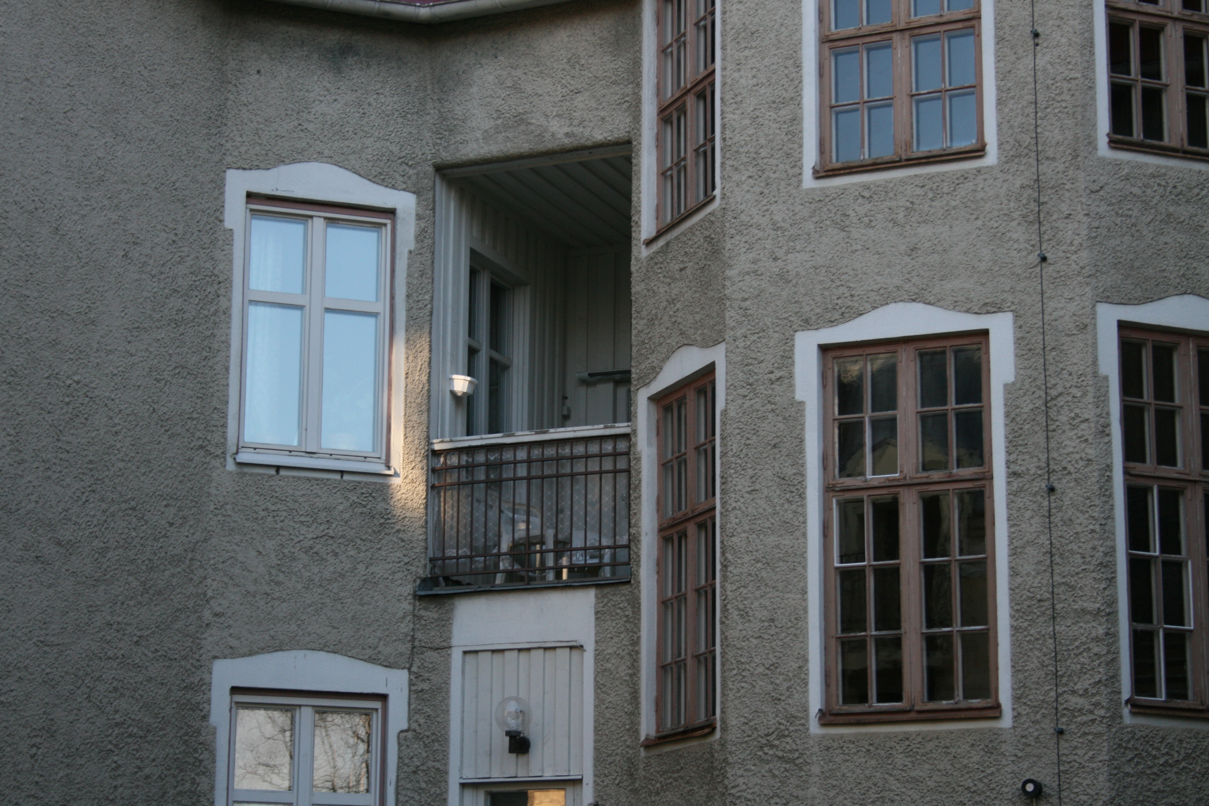 Indragen balkong och smårutiga trapphusfönster.