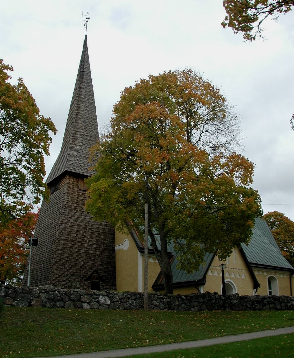 Exteriör bild av kyrkan med kyrkogård med omgivande mur. 