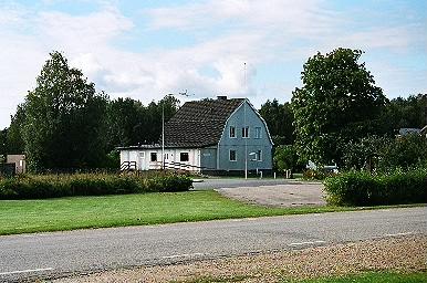 Församlingshemmet söder om Holsljunga kyrka och landsvägen, från NÖ.