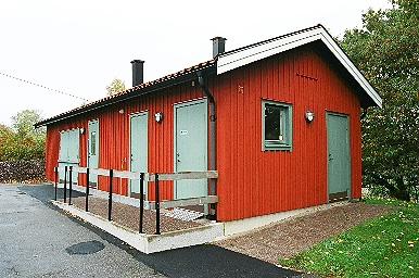 Ekonomibyggnad med vaktmästarkontor öster om parkeringsplatsen vid Tostareds kyrka, från SV.