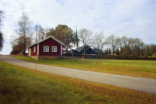 Sockenstugan i Dalstorp med kyrkan i bakgrunden.