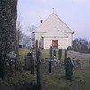 Bergums kyrka, västfasaden. Äldre gravstenar i förgrunden.