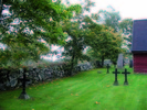 Kyrkogården omgärdas av en gammal stenmur i gråsten.Lönnar är planterade innanför kyrkogårdsmuren som en trädkrans.