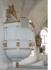 Predikstolen på norra sidan har femsidig korg prydd med kolonner och snidade, förgyllda ornament