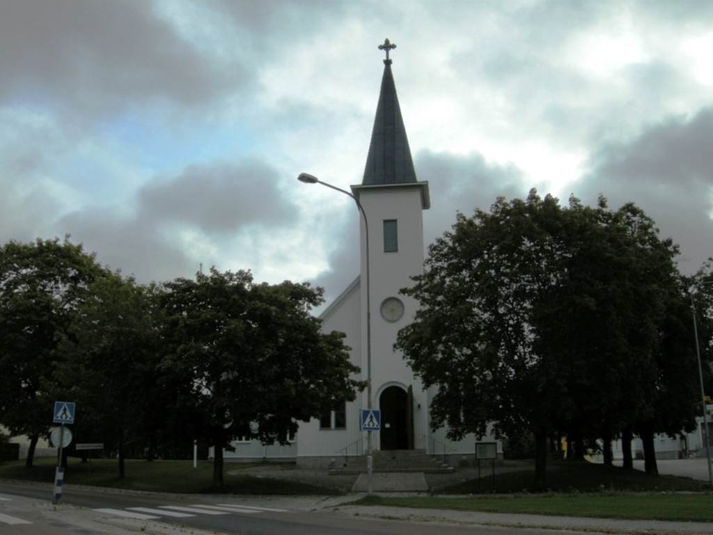 Strömsbro kyrka sedd från väster. Strömsbrovägen löper längs tomtgränsen.
