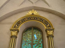 Altaruppsatsens änglabåge som symboliserar himlavalvet inramar
Per Anderssons bildfönster med trosbekännelsen.