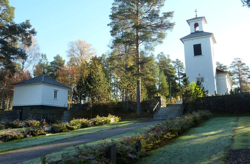 Kyrkan och gravkapellet sett från nya kyrkogården, invigd 1930. Mot gravkapellets källare syns fina stenarbeten, liksom i muren med trappa mot kyrkotomten.