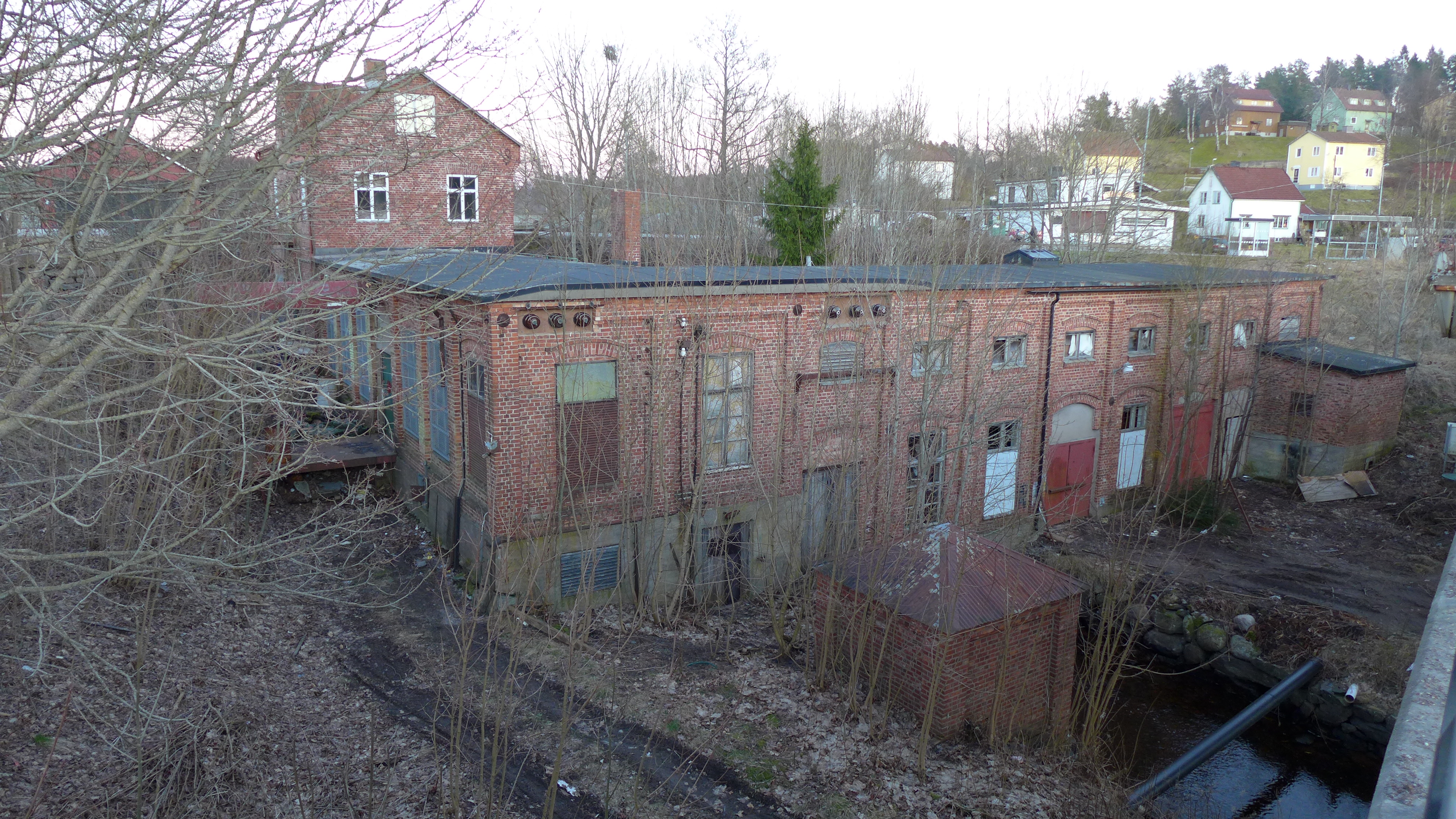 Den vinkelbyggda fabrikbyggnaden och Stigens östra (övre) ligger i blickfånget från Vänersborgsvägen mitt inne i Stigens samhälle. 