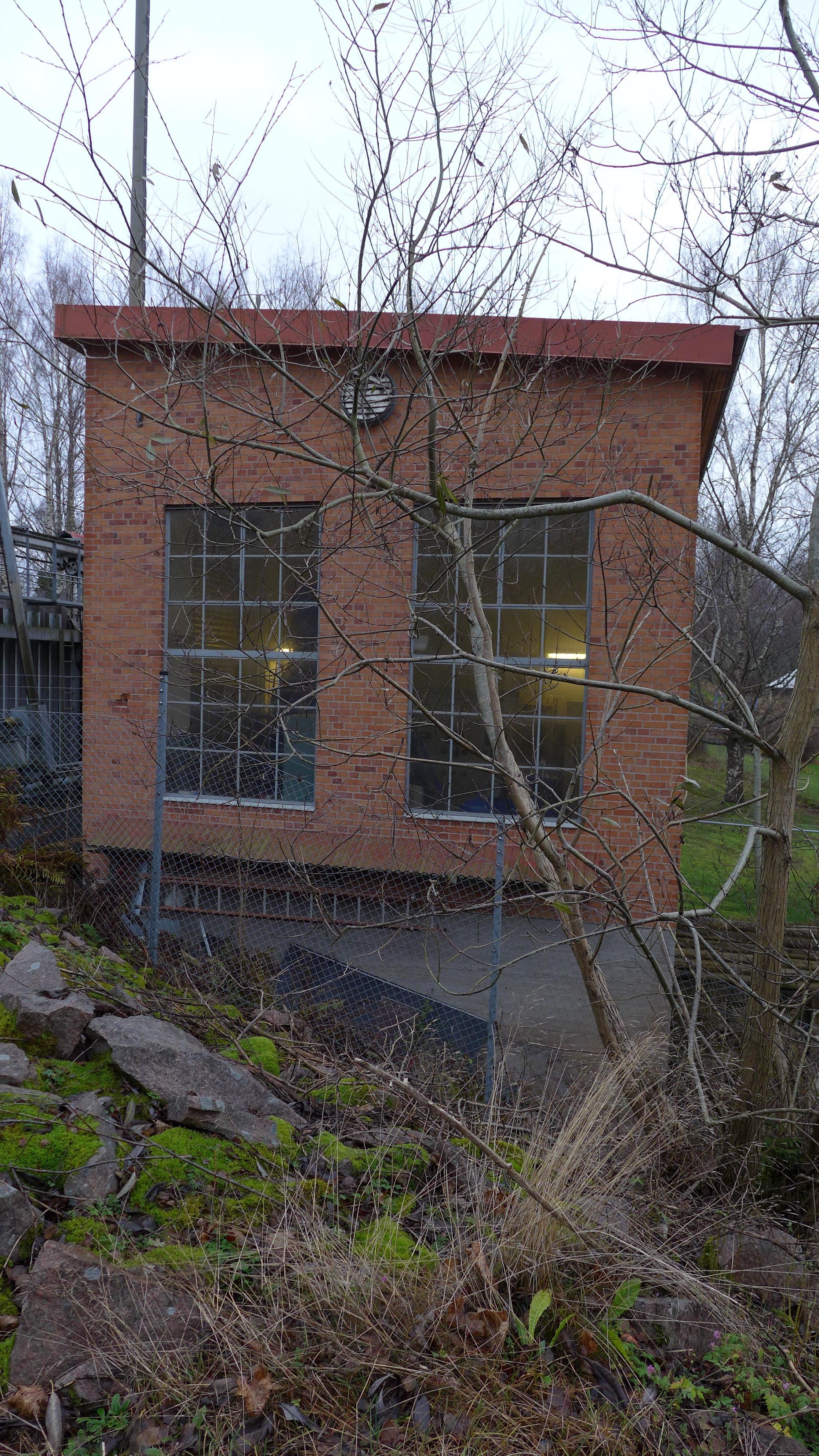 Kraftstationen har ett pulpettak med på en senare tid plåtklädd takfot. Järnfönstren är gråmålade. 