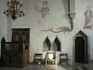 Korbänk, svarvad stol, väggnischer, muralmålningar samt sakristiingång, längs med och på korets N vägg. 