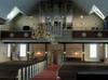 Interiör mot öster med den i klassisk anda smyckade läktaren och moderna orgeln.