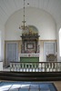 Högaltaret med altaruppsatsen vilka flankeras av de båda sakristiingångarna, i förgrunden altarskranket och kormattan.