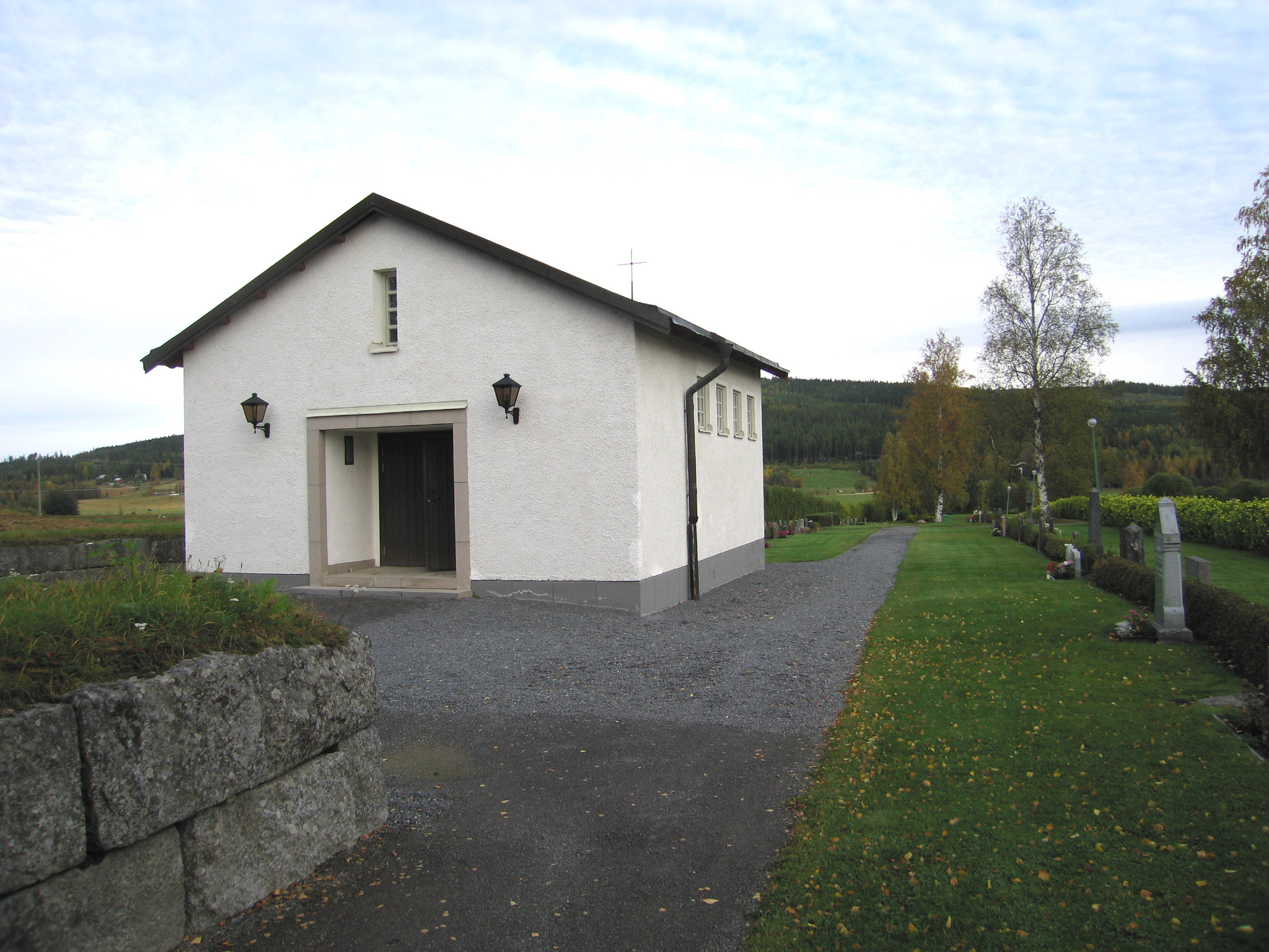 Långsele kyrkas kyrkogård, Gravkapellet, vy från sydöst. 

I nordväst återfinns ett gravkapell ritat 1957-58 av länsarkitektkontoret i Östersund. Betongstomme med utvändig sprutputsfasad, vit målning, sadeltak med falsad kopparplåt. Entré mot söder med naturstensinfattad omramning, pardörr beslagen med falsad kopparplåt. Högt sittande enluftsfönster mot väster och öster, nio spröjsade glas, grå målning. Slätputsade fönsteromfattningar.