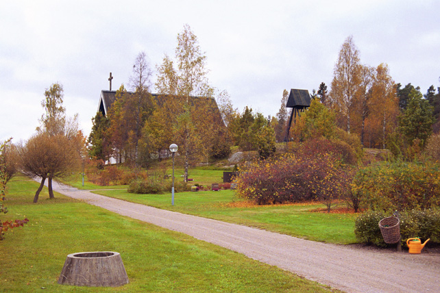 Del av kyrkogården, kyrkan och klockstapeln från norr.