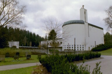 Krematoriebyggnaden på S:t Sigfrids griftegård sedd från parkeringen i norr. Till höger i bild ses Uppståndelsens och längst till vänster Hoppets kapell. Minnets kapell är beläget i vinkelbyggnadens källarvåning, skymt av muren.