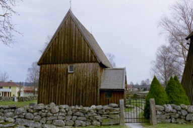 Hedareds kyrka och kyrkogårdsmur med grind från väster.
