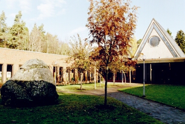 Lextorpskyrkans sydvästra gavel sedd från innergården. Stenen har bedömts vara en offersten från bronsåldern.