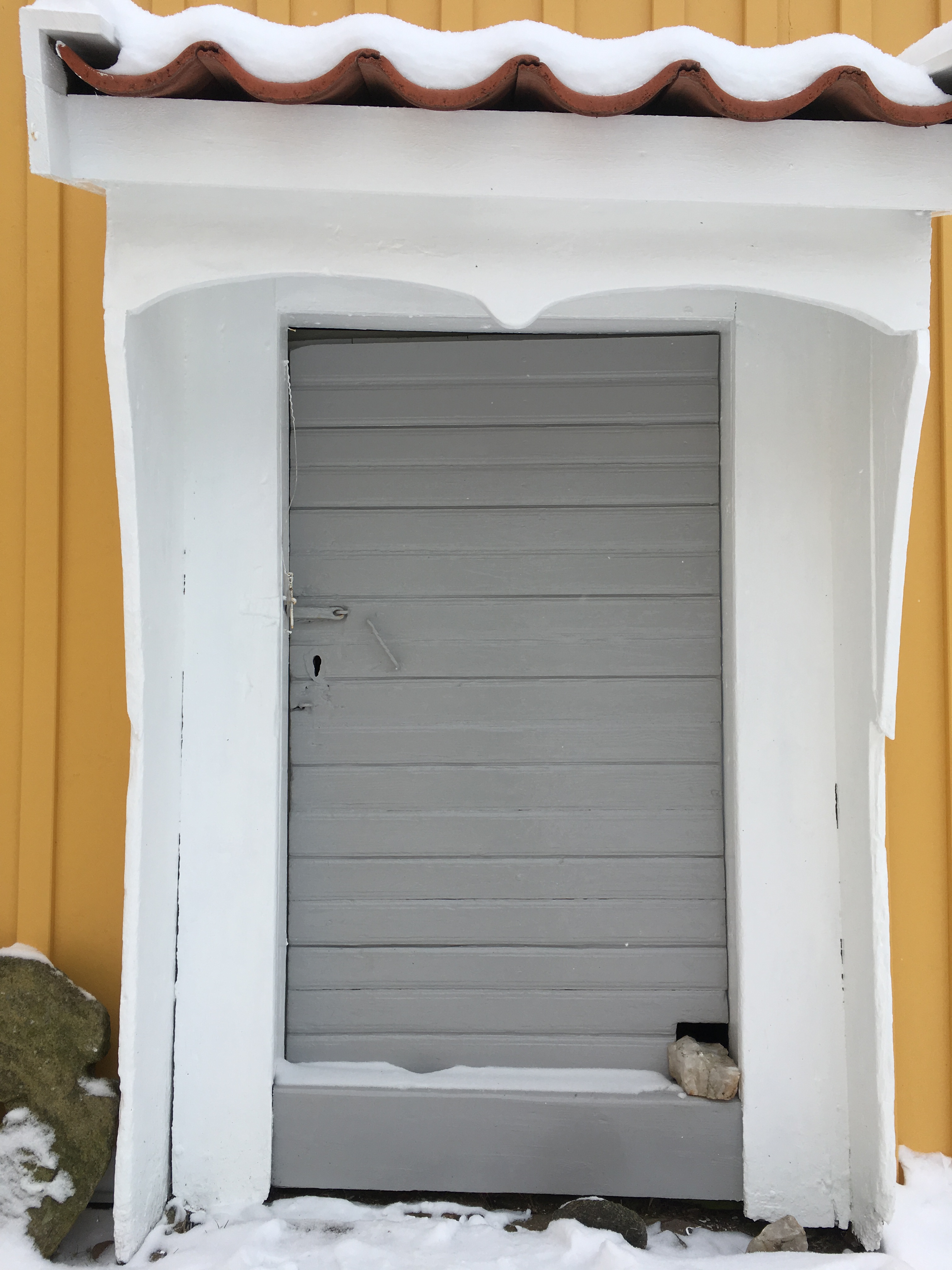 Närbild på ingången med dörr som uppskattningsvis kan dateras till 1800-talets början och bislag. 