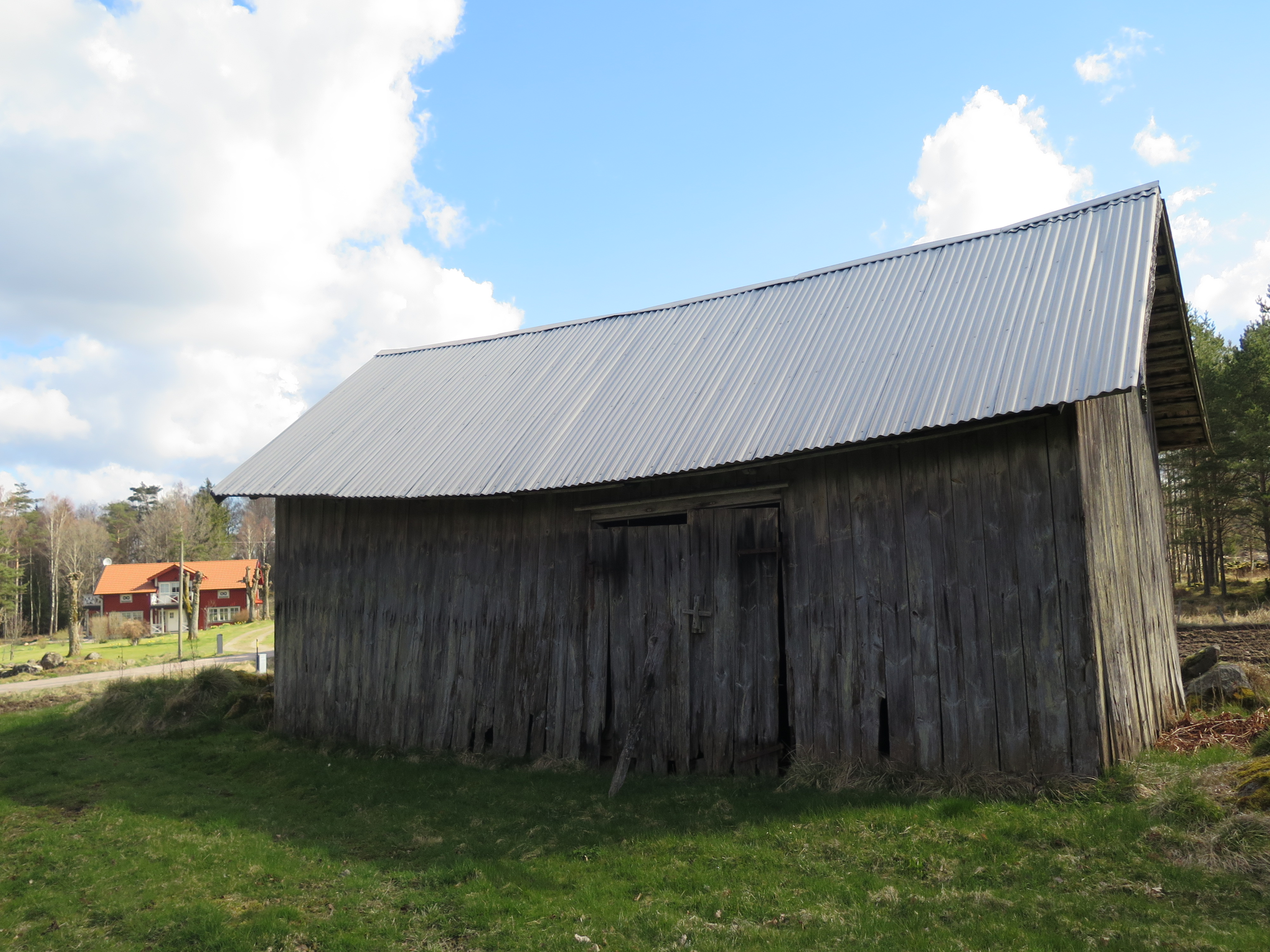 En liten bod, liksom ladugården omålad, hör till gårdsmiljön på Brunnsåker. 