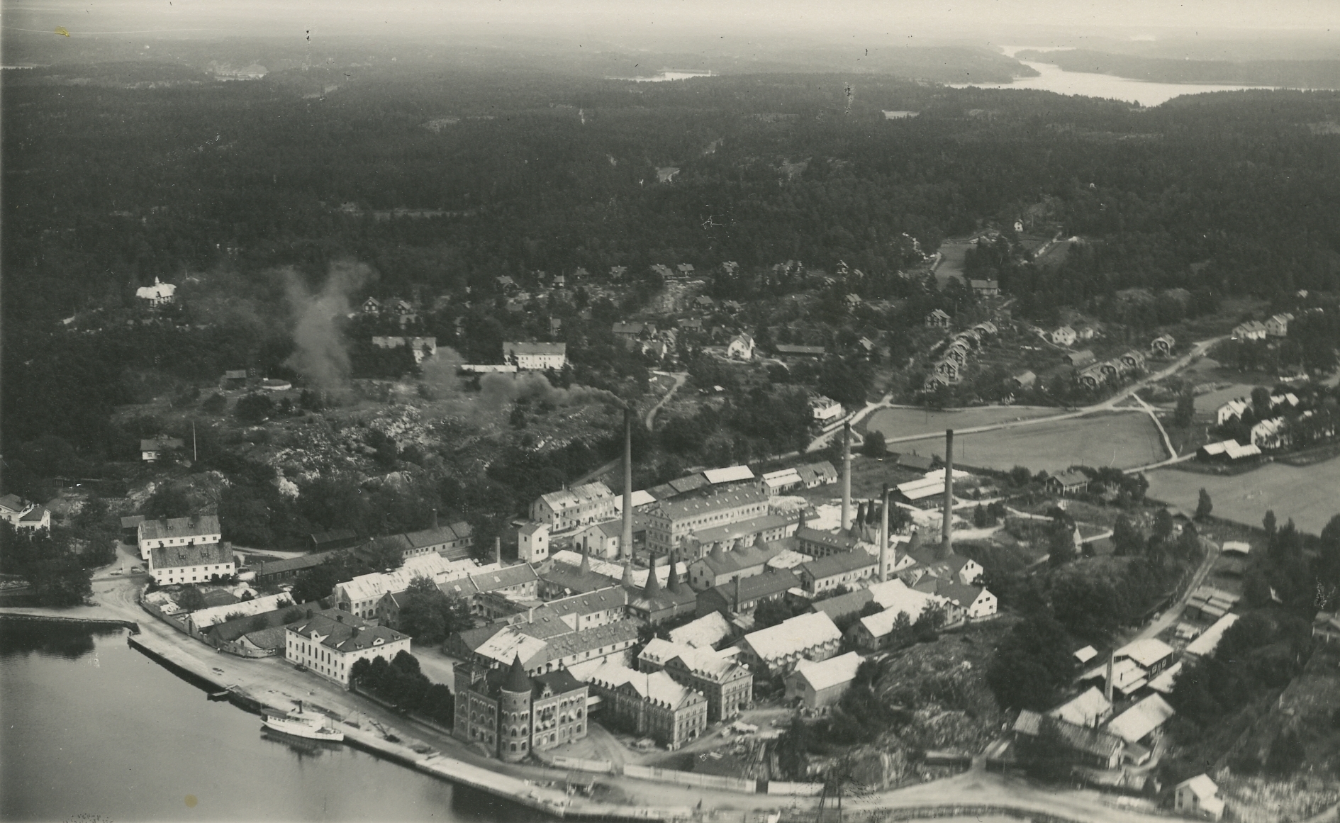 Flygfoto över fabriksområdet med hamnen i förgrunden. 1930-tal.