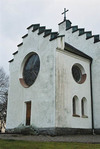 Del av kyrkans västgavel med sakristian och korfönster. Foto från nordost.