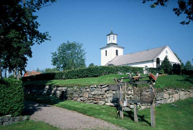 Västra Ämterviks kyrka med kyrkogård från so.