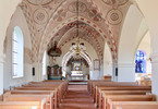 Valvens medeltida kalkmålningar präglar kyrkorummet. Till höger i bild skymtar den södra korsarmen som sedan 1963 fungerar som dopkapell.