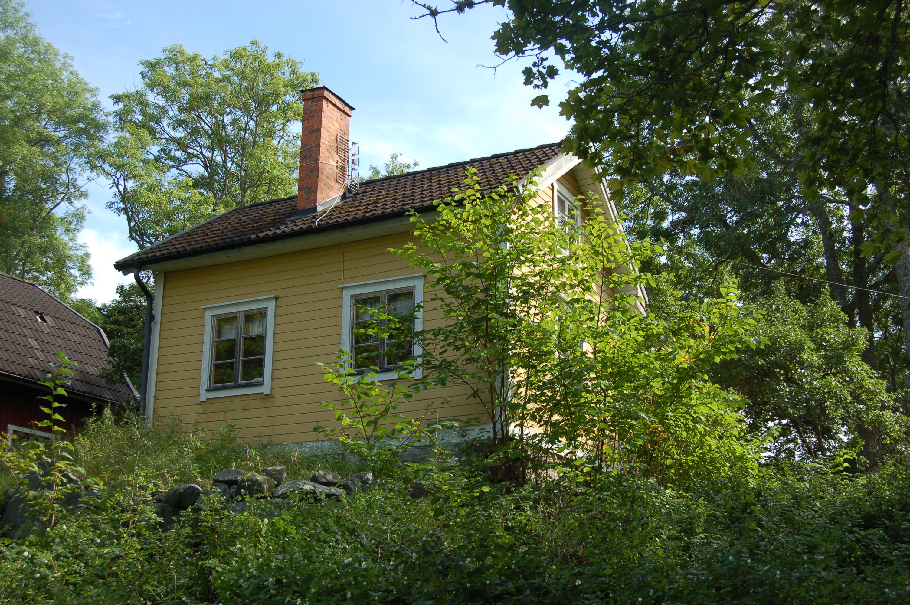 Bostadshus med fasader av liggande gulmålad panel.