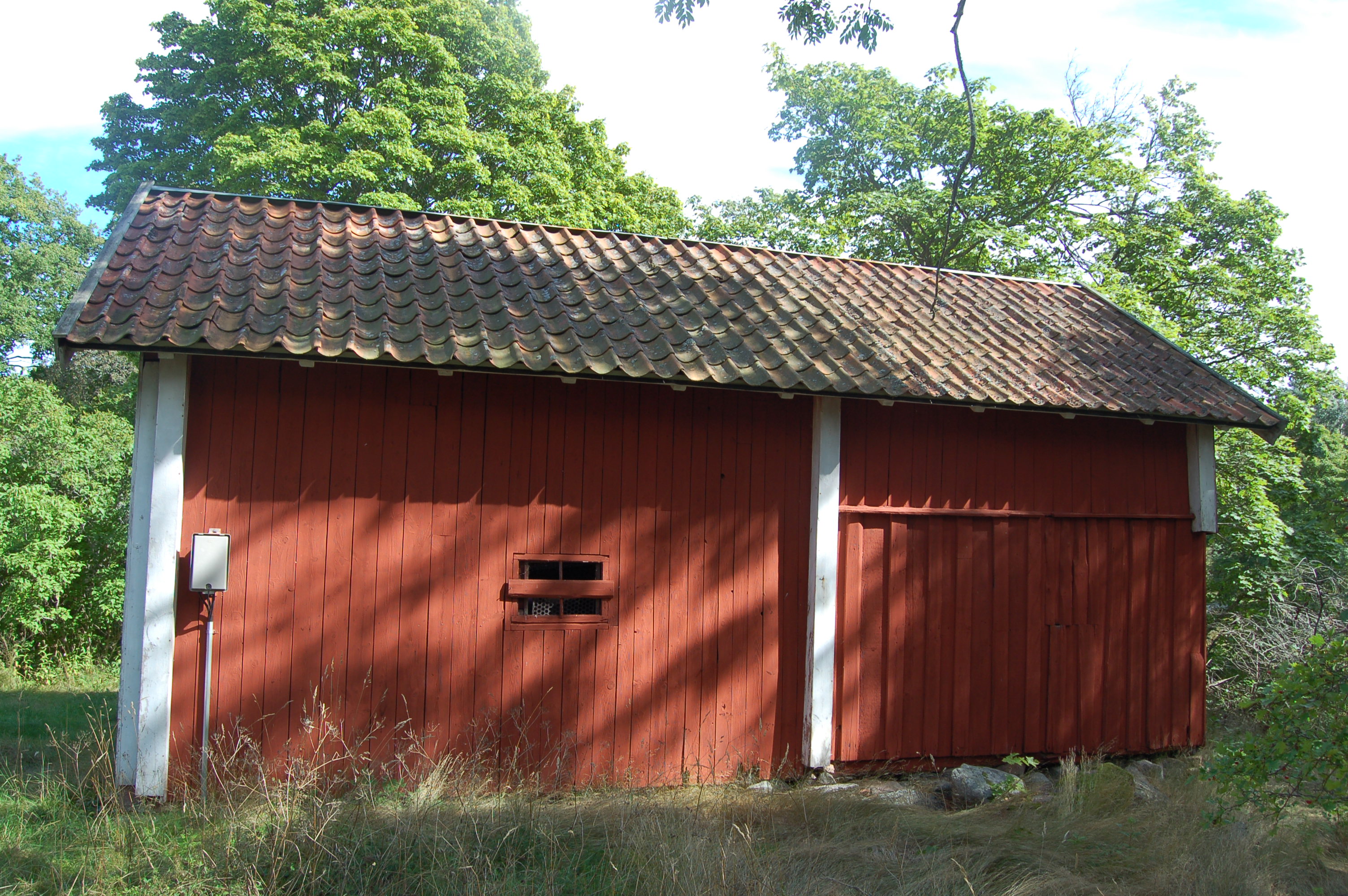 Fasaderna är klädda med stående brädpanel och bred locklistpanel.